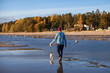 man walking with a dog on the shoreline spit on the background of the autumn woods